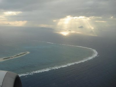 [photo: view from airplane of light rays shining through the clouds]